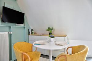 a white table with two chairs and a tv at Gîte du Merlin in Plumergat