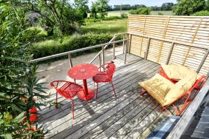 a deck with a table and chairs and a couch at Gîte du Merlin in Plumergat