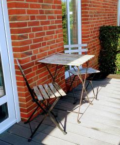 a table and two chairs sitting next to a brick wall at HausJensen in Niebüll