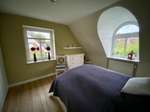 a bedroom with a bed and two windows at HausJensen in Niebüll