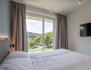 a bedroom with a bed and a large window at stay flex Hotel & Apartment in Hertenstein
