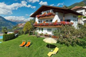 a house on a hill with chairs and an umbrella at Haus Bernhard in Schenna