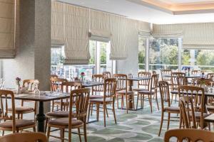 a dining room with tables and chairs and windows at Amalia Hotel Athens in Athens