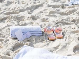 a pair of flip flops and a towel and a pair of sandals on at Mercure Rio de Janeiro Barra da Tijuca in Rio de Janeiro