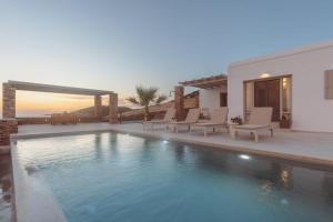 a swimming pool with chairs and a house at Bonatsa House in Agios Georgios