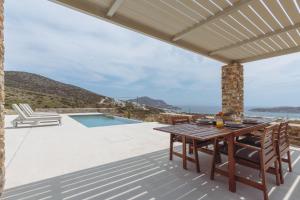 a patio with a table and chairs and a swimming pool at Bonatsa House in Agios Georgios