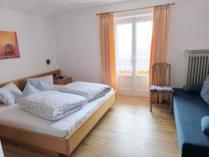 a bedroom with a bed and a couch and a window at Haus Bernhard in Schenna +15 photos