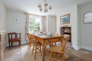 a dining room with a table and chairs and a fireplace at Westport Cottage in Wareham