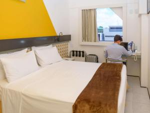 a man sitting at a desk in a hotel room at Ibis Budget Salvador in Salvador