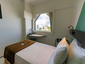 a bedroom with a bed and a window and a sink at Ibis Budget Salvador in Salvador