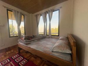 a bedroom with a bed and two large windows at Bikash Homestay in Mangpu
