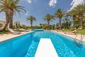 a swimming pool with palm trees in the background at Villa Oasi di Pace in Nardò