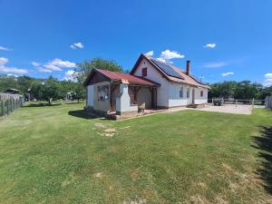 a small white house with a grass yard at Boróka Vendégház Gerjen in Gerjen