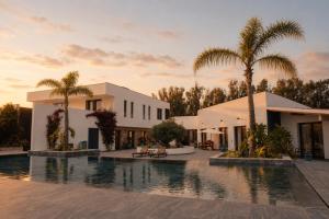 a villa with a swimming pool and palm trees at Lagoa Beach House B&B - Breakfast included in Serra do Bouro