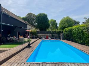 a swimming pool in a yard with a wooden deck at La Villa d'ElodibiZa, 45mn de Paris en train avec piscine ! in Écuelles