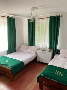 two beds in a room with green curtains at NOCLEGI NOVA in Krasnobród