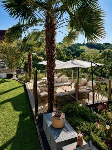 a patio with a palm tree and chairs and umbrellas at Maison Maün in Gelos