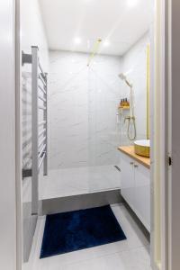 a bathroom with a shower and a blue rug at Kaposvár Deluxe Apartman in Kaposvár