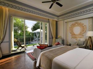 a bedroom with a bed and a large window at Raffles Udaipur in Udaipur