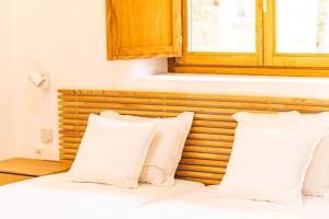 a bed with white pillows and a wooden headboard at La Cueva Rural Boutique Villa in La Focella