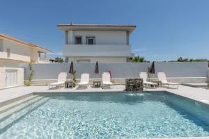 a swimming pool with chairs and a house at Villa Vibella in Laganas