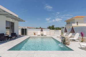 a swimming pool on a patio with chairs and umbrellas at Villa Vibella in Laganas