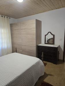 a bedroom with a bed and a dresser and a mirror at Quinta Real Kiwibee in Barrô