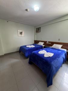 two beds in a room with blue sheets at Hotel Harmony in Caracas +16 photos