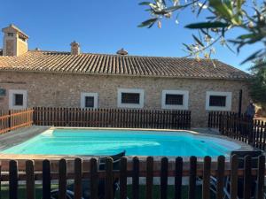 a swimming pool in front of a house with a fence at Casa del Labrador in Jumilla