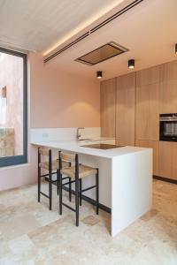 a kitchen with a white counter and chairs at Room in Historic Knights House at the Marina in Senglea
