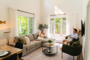 a man and woman sitting in a living room at Java with Private Spa & Games, Lake & Golf in Saint-Raymond