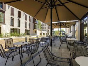 an outdoor patio with tables and chairs and umbrellas at ibis Styles Friedrichshafen in Friedrichshafen