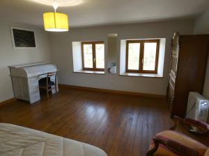 a bedroom with a bed and a desk and two windows at Gite Les Sources in Champagney