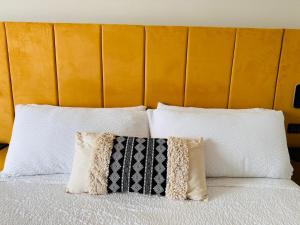a bed with white pillows and a orange headboard at Hotel Ti' Pelican in Saint-Pierre