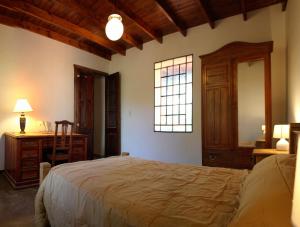 a bedroom with a bed and a desk and a window at Cabañas Estancia Balumba in Capilla del Monte