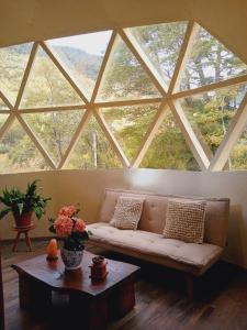 a living room with a couch in front of a large window at Domos Blackdomes in Las Trancas