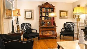 a living room with three chairs and a book shelf at The Queens House in Agrigento