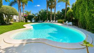 a large swimming pool in a yard with palm trees at The Queens House in Agrigento