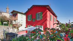 a red house with green shutters on a street at B&B SASSO DI ROCCA in Gaggio Montano