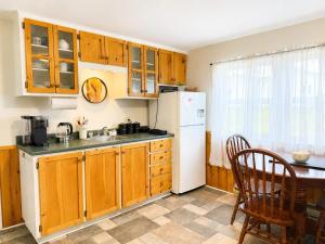 a kitchen with wooden cabinets and a white refrigerator at Gus & Nellie's Place in Twillingate