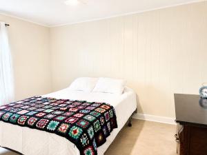 a bedroom with a bed with a colorful blanket on it at Gus & Nellie's Place in Twillingate +4 photos
