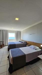 a hotel room with two beds and a window at Flat vista Mar -conforto e estilo em Ponta Negra-Natal in Natal +10 photos