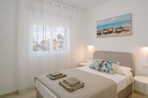 a white bedroom with a bed with towels on it at Myrtiana 10 in Oroklini