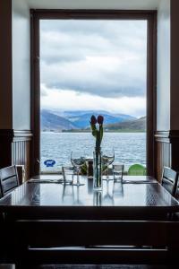 une table avec un vase de fleurs au-dessus d'un bateau dans l'établissement The Arch Inn, à Ullapool