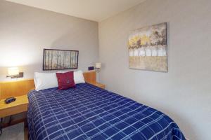 a bedroom with a blue bed and a desk and a painting at River Bank Lodge 2924 in Keystone