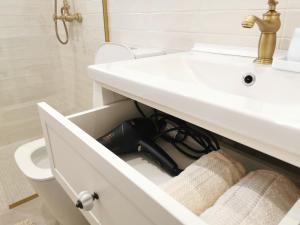 a bathroom with a white sink with a black charger in a drawer at Casa Olive Costinești in Costinesti