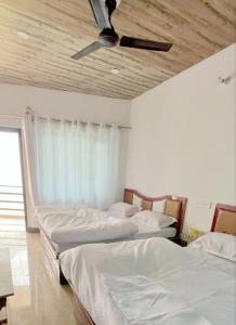 a room with three beds and a ceiling fan at Trishool inn residency in Chandrāpuri
