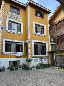 a yellow and white building with plants in front of it at Golden Mud in Srinagar