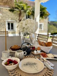 a table with plates and bowls of food and a vase of flowers at Maison Maün in Gelos