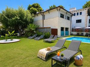a yard with chairs and a pool and a house at Hotel Sitges in Sitges